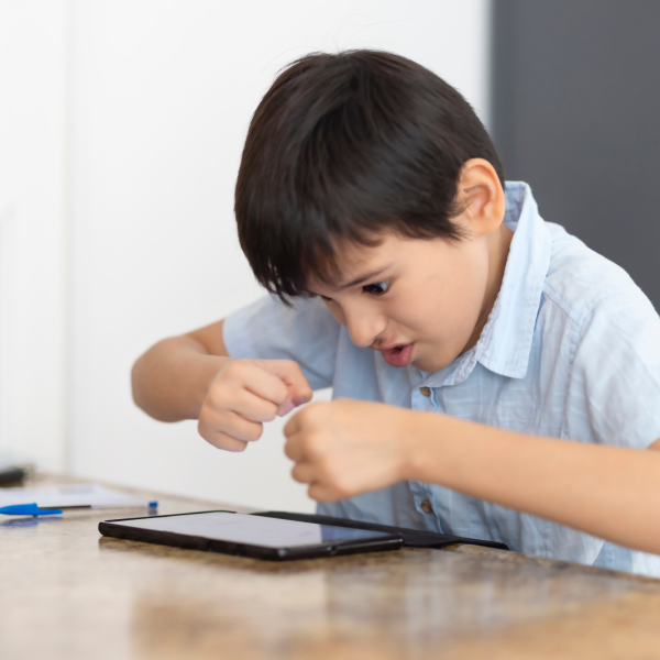 Child showing frustration and tension while working on a tablet, illustrating attention and emotional regulation challenges in ADHD